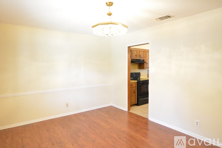 A room with a wooden floor and a doorway leading to a kitchen.