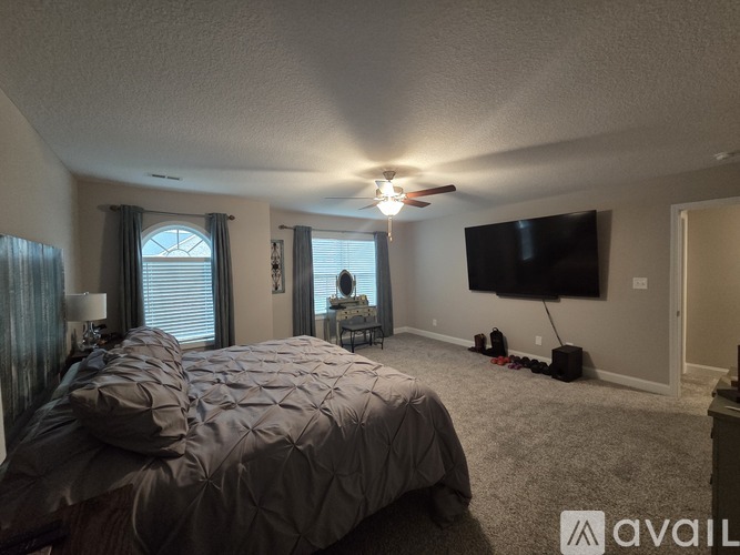 A bedroom with a large bed and a flat screen TV mounted on the wall.