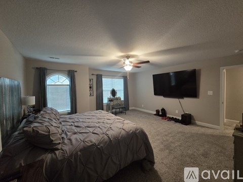 A bedroom with a large bed and a flat screen TV mounted on the wall.