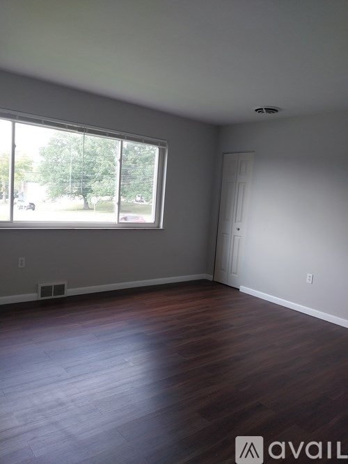 A room with a large window and wooden floors.