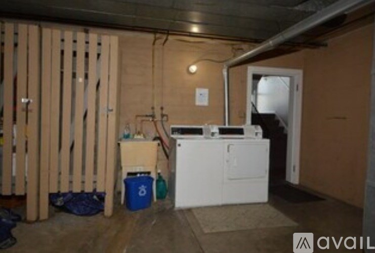 A room with a white dishwasher and a blue bucket.