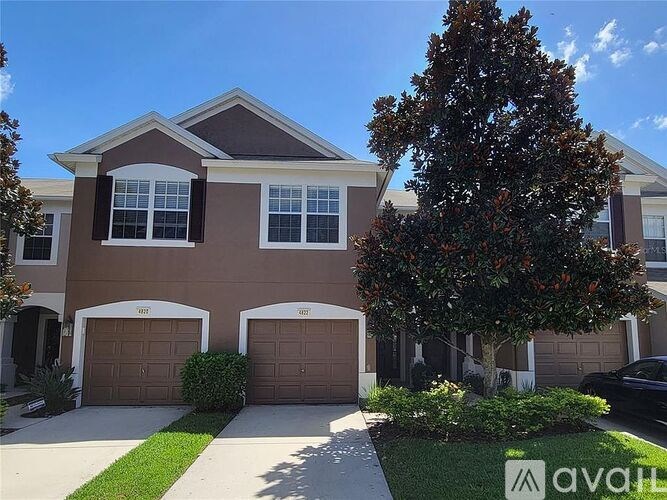 A house with a brown facade and a large tree in front.