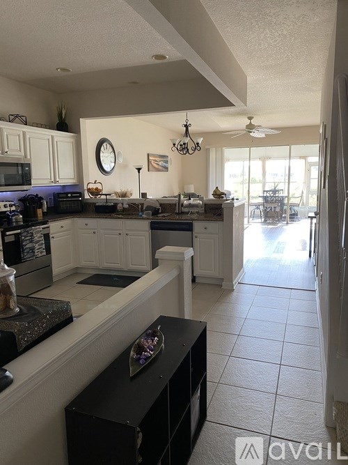 A kitchen with white cabinets and a black island.