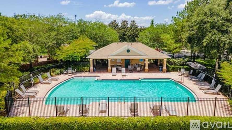 A pool surrounded by trees and a pavilion.