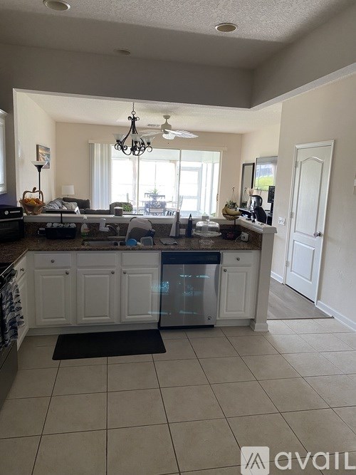 A kitchen with white cabinets and a black mat on the floor.