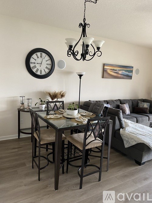 A dining room with a table set for four and a chandelier hanging from the ceiling.