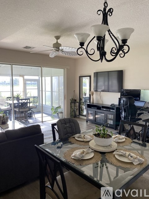 A living room with a glass table and a chandelier.
