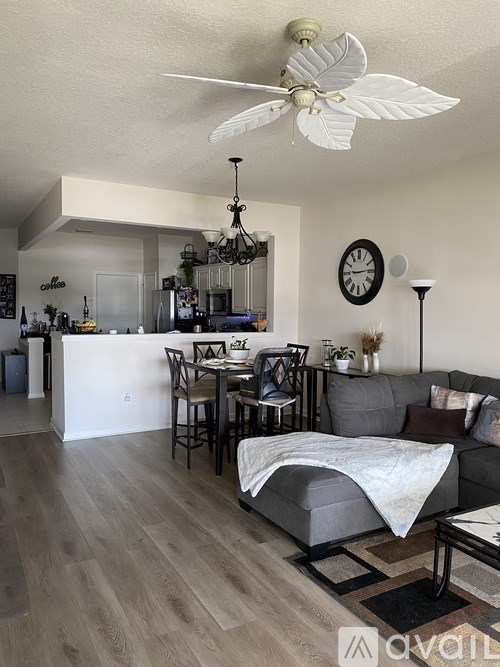 A living room with a grey couch and a white ceiling fan.