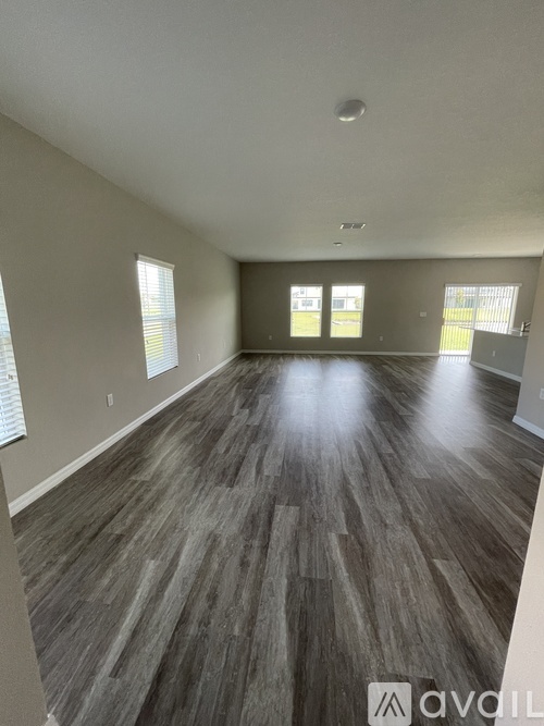 A spacious room with wood flooring and large windows.
