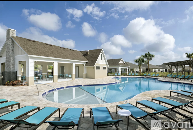 A pool surrounded by sun loungers and a building in the background.