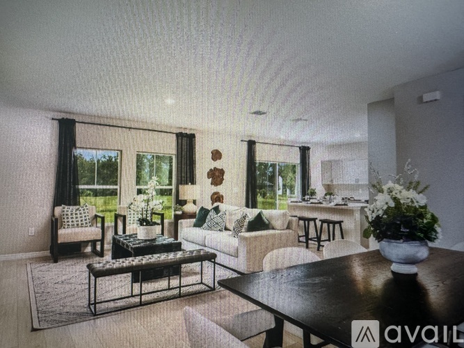 A living room with a couch, coffee table, and a large window with curtains.