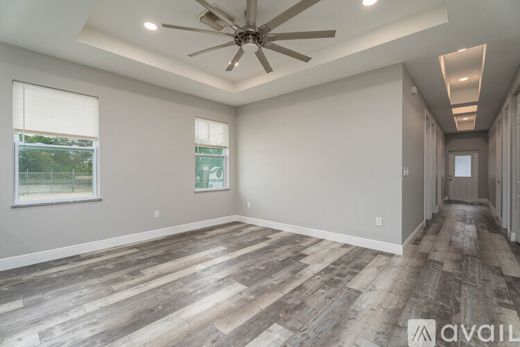 A spacious room with wooden flooring and a ceiling fan.