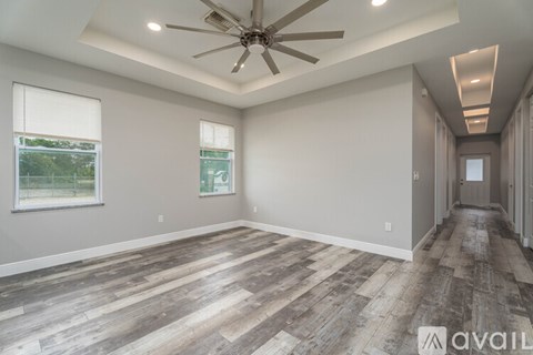 A spacious room with wooden flooring and a ceiling fan.
