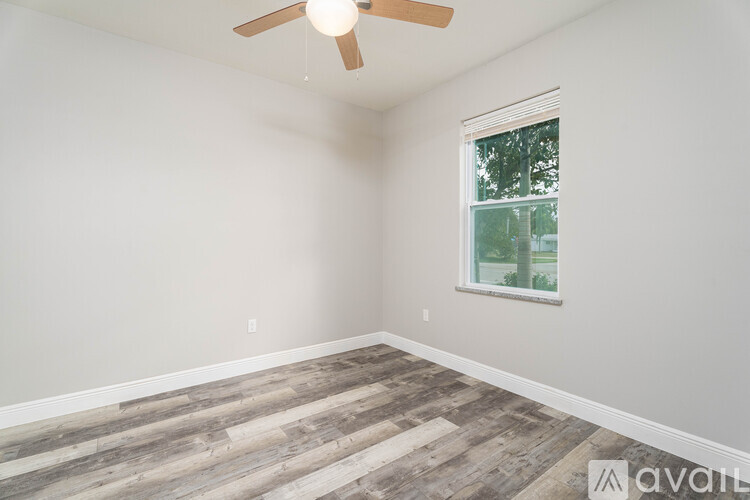A room with a ceiling fan and a window with a view of trees.