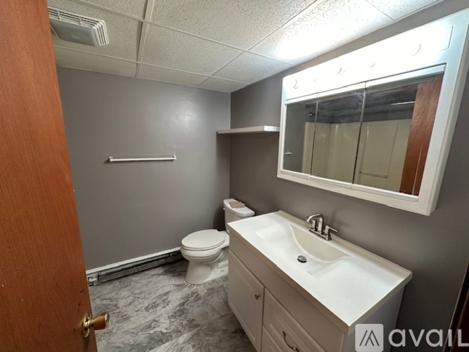 A bathroom with a toilet, sink, and mirror.