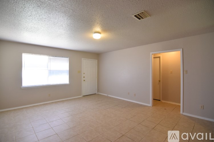 A spacious room with a window and two doors.