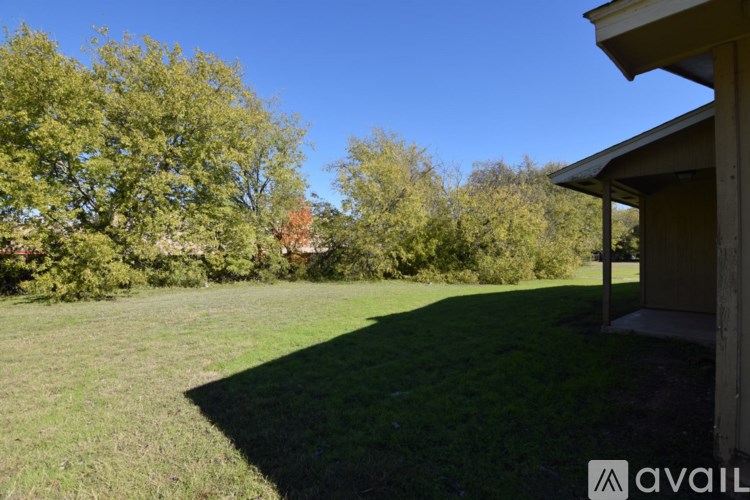 A grassy area with trees and a building in the background.