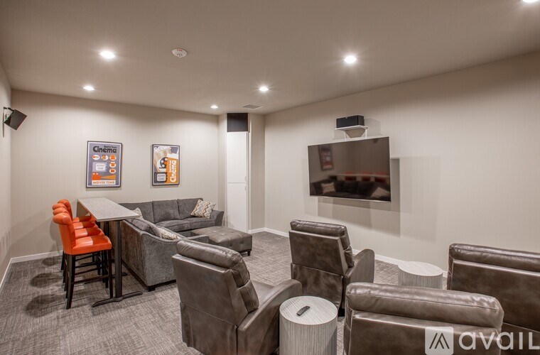 A cinema room with a row of seats and a screen on the wall.