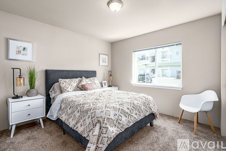 A bedroom with a bed, nightstand, chair, and window.