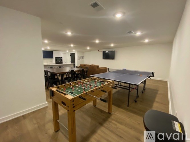 A table tennis table is in the middle of a room with a kitchen area in the background.