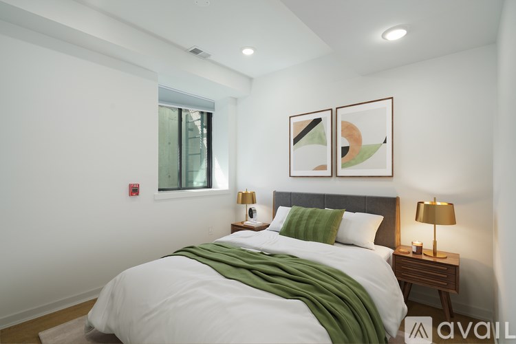 A bedroom with a bed, two lamps, and two framed pictures on the wall.
