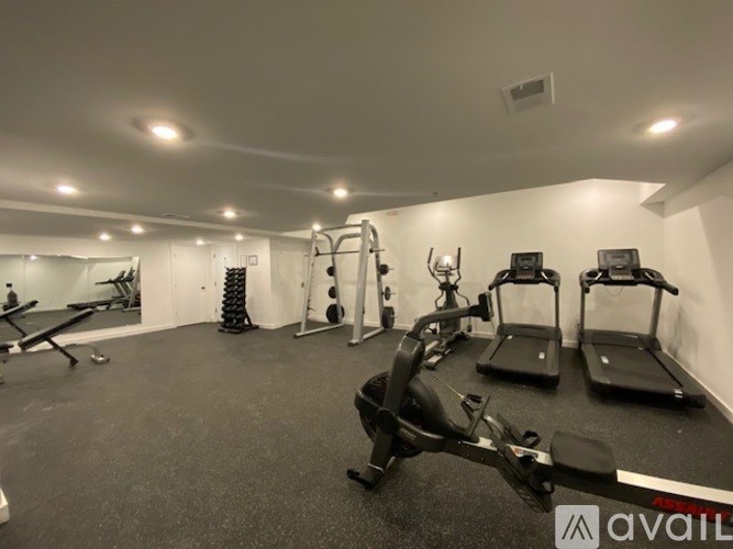 A gym with a row of treadmills and weights.
