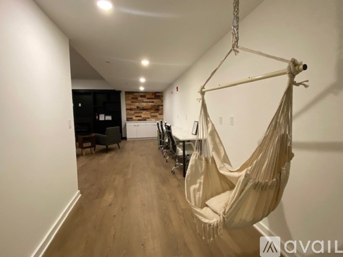 A hammock is suspended in a room with wooden flooring and a white wall.