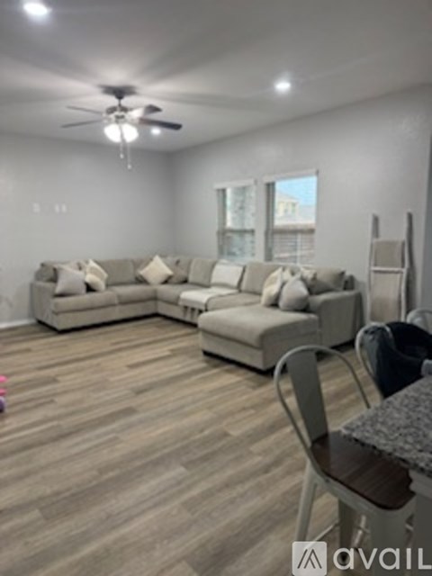A living room with a large sectional sofa and a ceiling fan.
