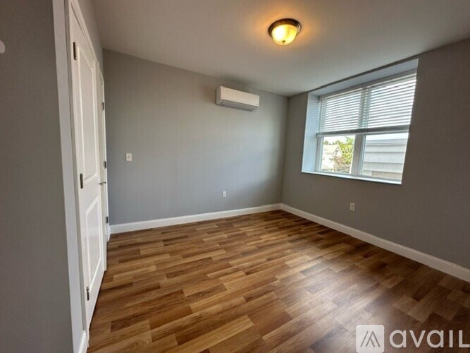 A room with wooden flooring and a window with blinds.