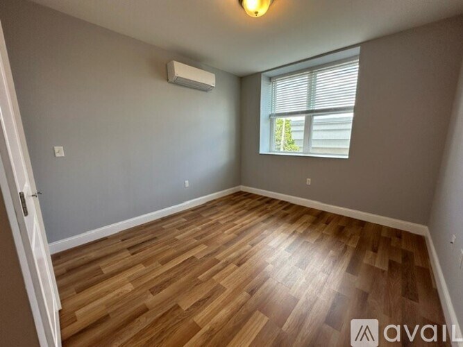 A room with wooden flooring and a window with blinds.