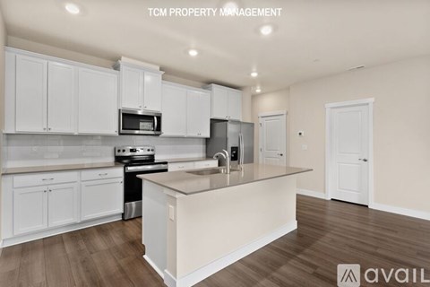 A kitchen with white cabinets and a wooden floor.