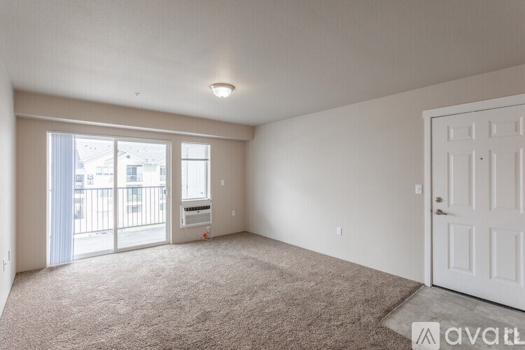 A room with a carpeted floor and a sliding glass door leading to a balcony.