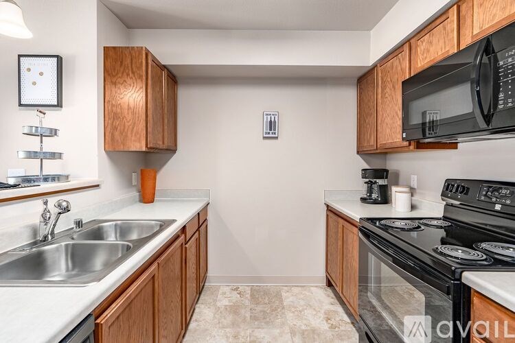 A kitchen with wooden cabinets and a black microwave.