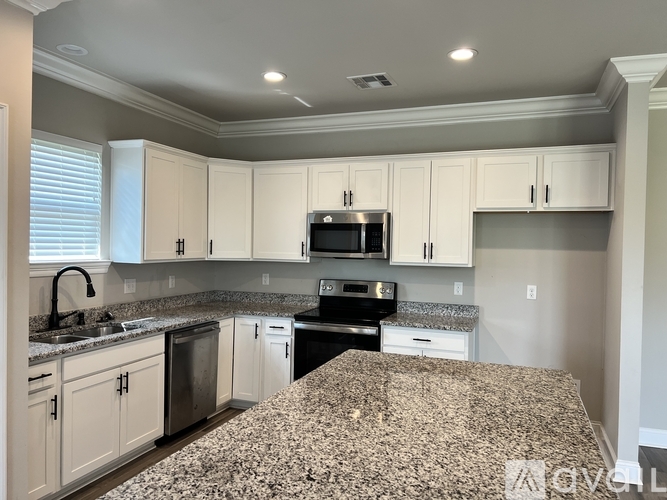 A kitchen with granite countertops and white cabinets.