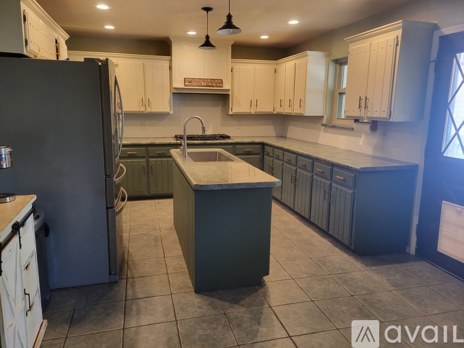 A kitchen with a black refrigerator and white cabinets.