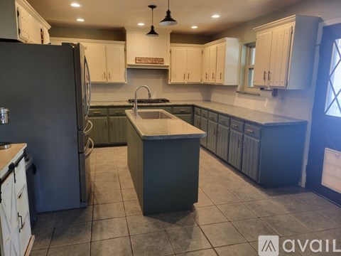 A kitchen with a black refrigerator and white cabinets.