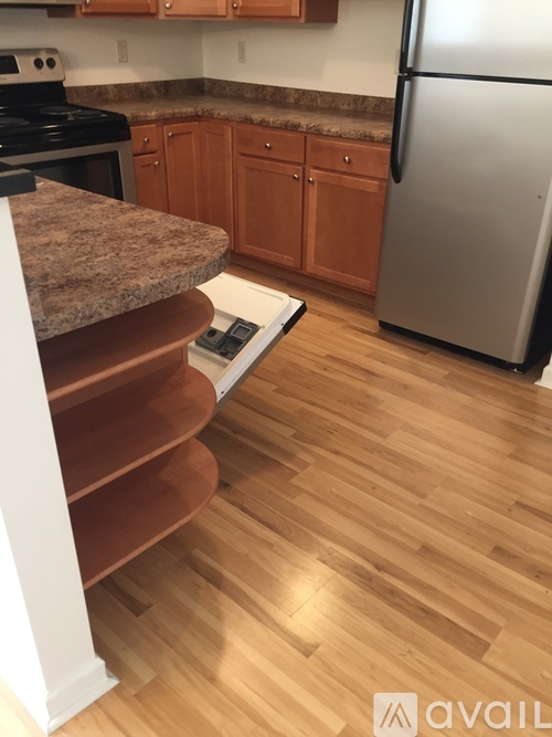 A kitchen with a stove, oven, refrigerator, and wooden floors.