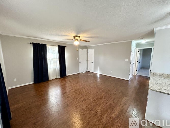 A spacious room with wood flooring and a ceiling fan.