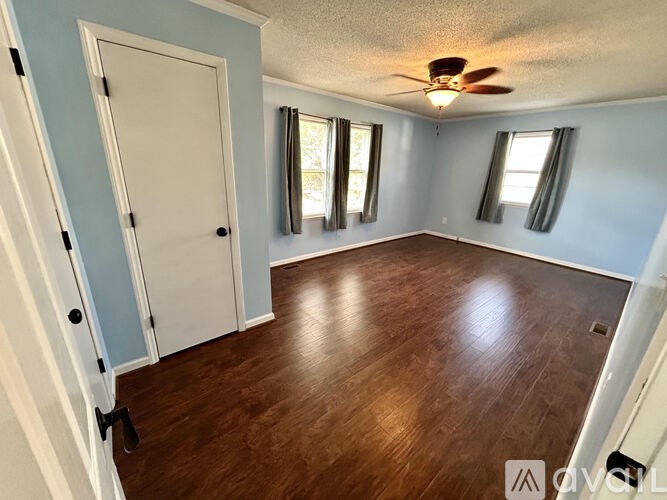 A room with a ceiling fan and wooden flooring.