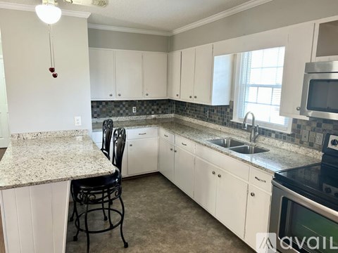 A kitchen with white cabinets and a granite countertop.