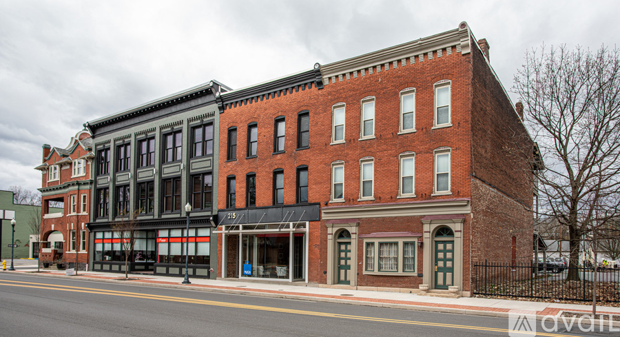 A red brick building with a black awning sits on a street corner.