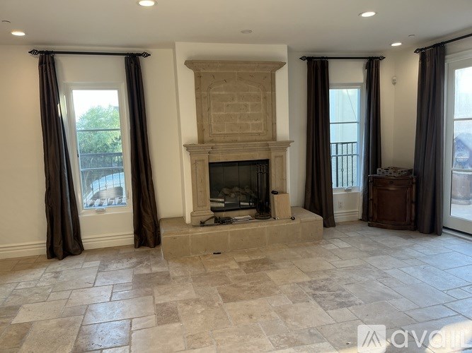 A large, empty room with a fireplace and a stone floor.