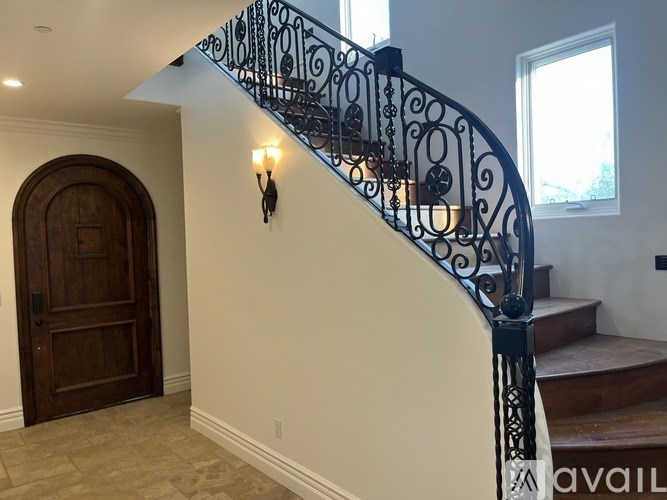 A staircase with a black wrought iron railing and a wooden door at the bottom.