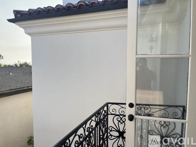 A white house with a black iron railing.