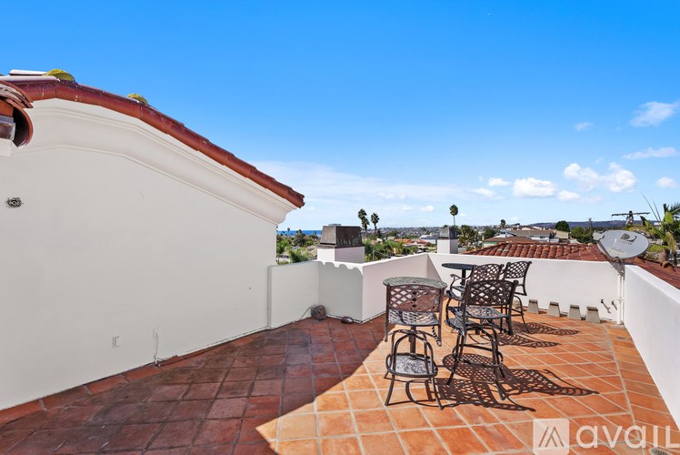 A white house with a balcony and a patio table.