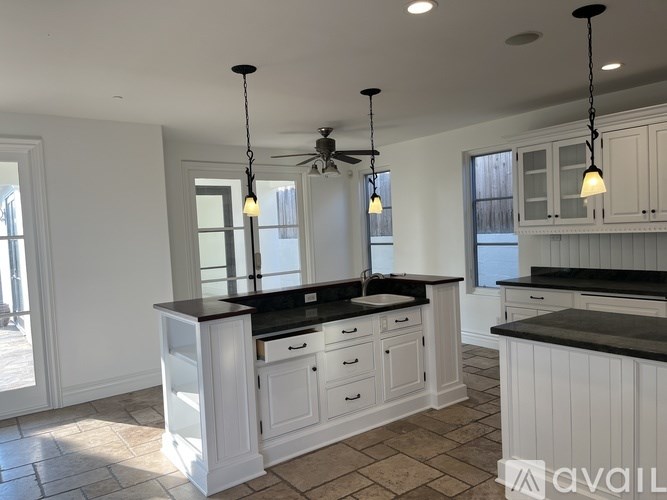 A kitchen with white cabinets and black countertops.
