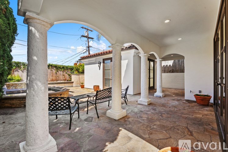 A patio with a table and chairs under a white arch.