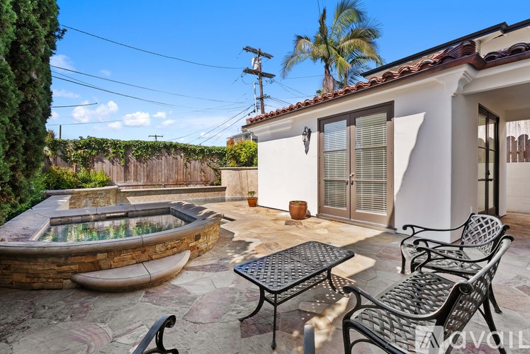 A patio with a table and chairs overlooking a pool.