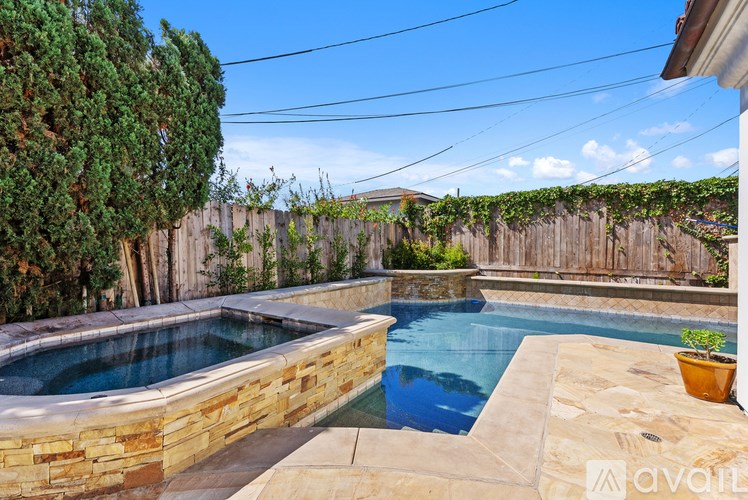 A backyard with a pool and a stone wall.