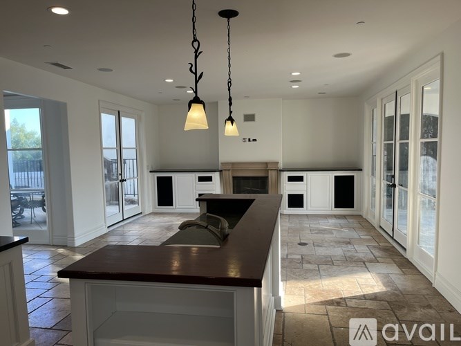 A modern kitchen with a dark brown countertop and pendant lights.
